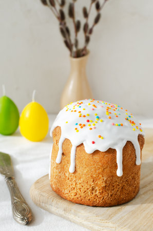 Traditional Ukrainian kulich on a cutting board on a white tablecloth with willow buds. The concept of festive Easter baking. selective focus. vertical orientation.の写真素材