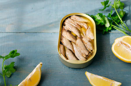 Canned fish with a sprig of parsley and lemon on a blue wooden table. Tinned fish concept. horizontal orientation. copyspace.の写真素材