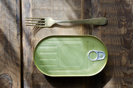 Can with a fork on a wooden table. Tinned fish concept. rustic style. horizontal orientation. top view.の写真素材
