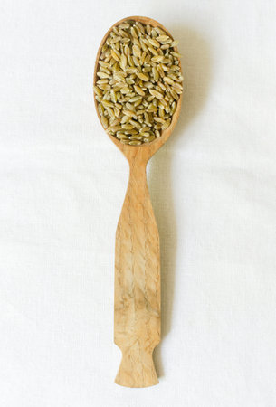 Raw freekeh or firik in a wooden spoon on a white background. concept of healthy eating. rustic style. vertical orientation. top viewの写真素材