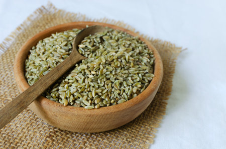 Raw freekeh or firik in a wooden bowl on burlap with a wooden spoon. concept of healthy eating. rustic style. vertical orientation. top view. selective focus.の写真素材