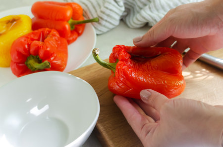 The process of preparing a salad with large red and yellow roasted peppers. Concept Traditional Italian dish. Vegetarian and vegan food. horizontal orientation.の写真素材