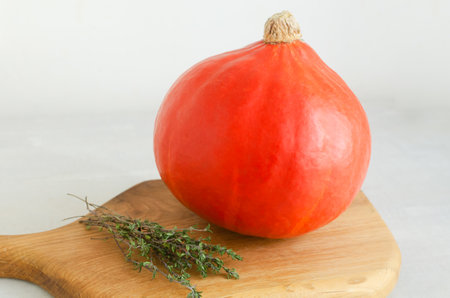 Orange Hokkaido pumpkin with thyme on a wooden cutting board. Concept of healthy food. Autumn mood. Horizontal orientation.の写真素材