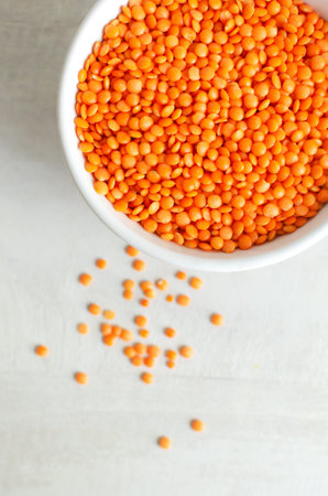 Orange lentils in a white bowl on a light background. The concept of proper nutrition. Vegan and vegetarian food. Vertical orientation. Top view. Copy space.の写真素材