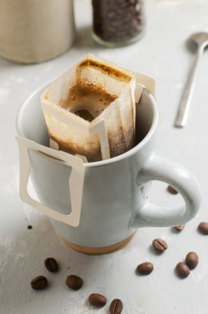 The process of brewing a bag Drip coffee into a cup on a gray background. A quick way to prepare a tasty and aromatic drink. Vertical orientation. Selective focusの写真素材