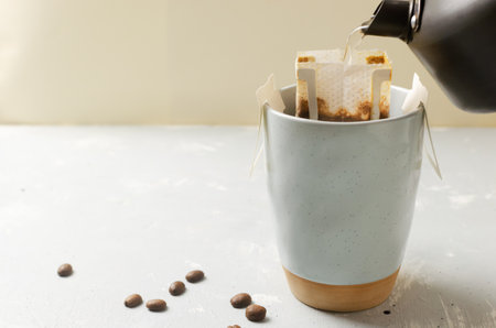 The process of brewing a bag Drip coffee into a cup on a gray background. A quick way to prepare a tasty and aromatic drink. Horizontal orientation. Selective focus. Copy spaceの写真素材