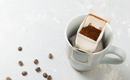 The process of brewing a bag Drip coffee into a cup on a gray background. A quick way to prepare a tasty and aromatic drink. Horizontal orientation. Selective focus. Copy spaceの写真素材