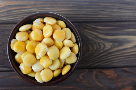 Lupine beans in a brown bowl on a wooden table. Italian food. Type of legumes. Healthy food concept. Horizontal orientation. Selective focus. Copy space. Top viewの写真素材