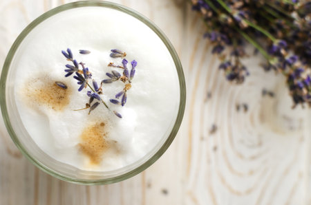 Large glass of hot Lavender Latte on a white wooden table with flowers in the background. Concept of high-quality coffee drinks. Horizontal orientation. Selective focus. Copy space. Top viewの写真素材