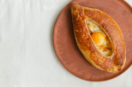 Adjarian khachapuri with egg yolk on a ceramic plate on the table. The concept of traditional...