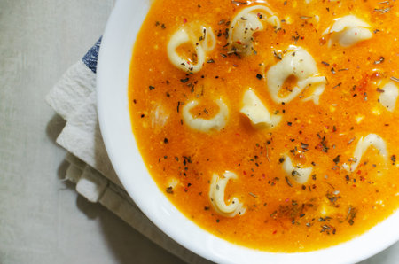 Tortellini soup with onion, garlic, celery, tomatoes and parmesan. Traditional Italian food concept. Selective focus. Horizontal orientation. Top viewの写真素材