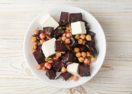 Beet Salad with chickpeas, feta and green sauce with butter and parsley in a white bowl on a wooden table. Healthy eating. Horizontal orientation. Selective focus. Top view.の写真素材