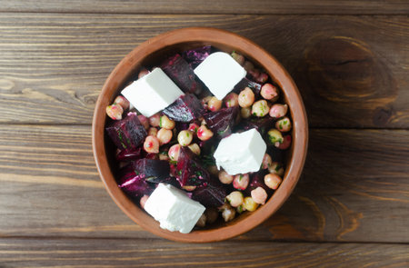 Beet Salad with chickpeas, feta and green sauce with butter and parsley in a ceramic bowl on a wooden table. Rustic style. Healthy eating. Horizontal orientation. Selective focus. Top view.の写真素材