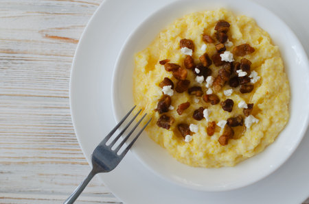 Traditional Hutsul banosh with bryndza and crispy cracklings in a white bowl on a wooden table. Authentic Ukrainian cuisine dish with a warm homely feel. Selective focus. Top view. Copy spaceの写真素材