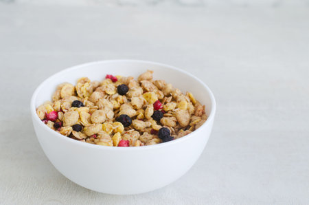 Healthy Homemade Granola with Dry Berries in a white bowl on a light background. Healthy eating...