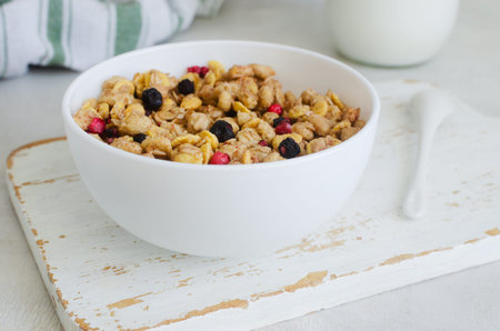 Healthy breakfast bowl with crunchy cereal, granola, cornflakes and dried berries on rustic wooden...