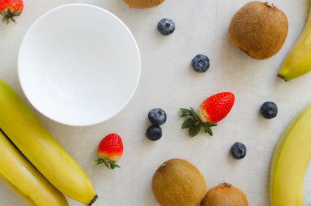 Ingredients for Banana kiwi smoothie: bananas, kiwi, blueberries and strawberries. Bright fruits for detox breakfast. Concept of fitness food or wholesome meal. Top view. Selective focusの写真素材