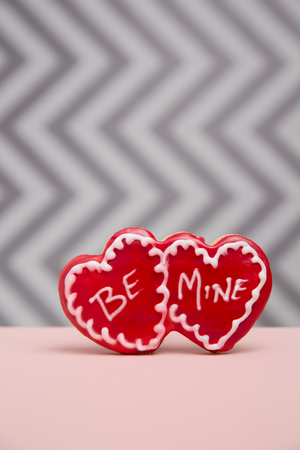 A red Cookie printed with Be Mine on a grey chevron background with pink foregroundの写真素材