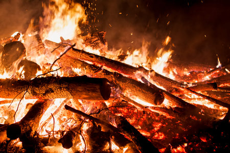 Logs burning in evening bonfire with sparks and embers
