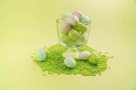 Easter eggs in a clear cup with green and yellow sprinkles on a bright green backgroundの写真素材
