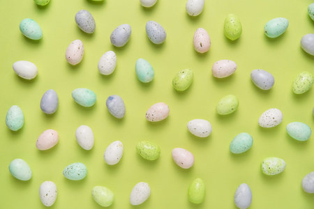 Flat lay of scattered pastel easter eggs on bright green background
