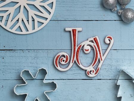 Word Joy on blue plank board background with cookie cutters, christmas ornaments, and snowflake shapesの写真素材