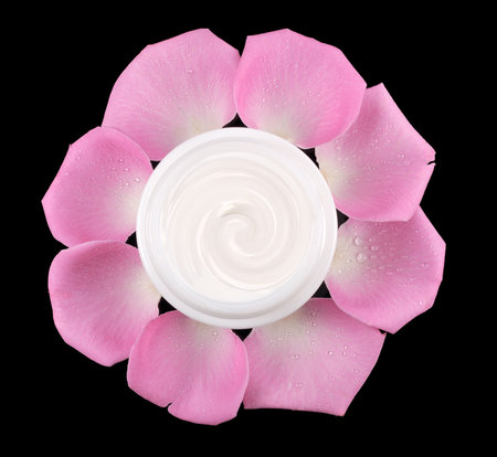 cosmetic face cream on a black background with rose petals