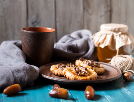 Romantic morning still life, in a rustic style with cookies, a glass jar of honey and scattered dates on a turquoise wooden backgroundの写真素材