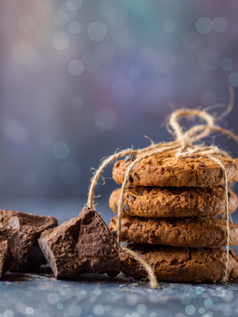Chocolate cookies, stacked and tied with a rope, pieces of black chocolate, on a textured background. Vertical layoutの写真素材