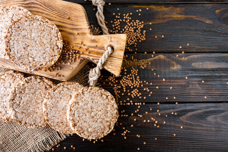 Airy, round, crisp buckwheat crispbread on wooden background with buckwheat scattered around, vintage board and burlap. top viewの写真素材