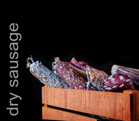 Traditional sausage and sausage with mold , jamon, bacon in wooden box isolated on dark background . Close-up. Element for designの写真素材