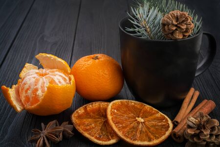Winter Christmas still life: tangerines, dried oranges, cinnamon sticks and anise stars on a textured, black, wooden background.の写真素材