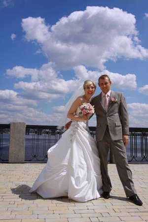 Bride and groom smiling and looking at the camera on a walkingの写真素材