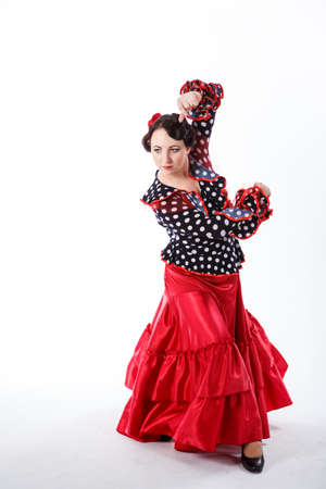 young beautiful brunette female spanish flamenco dancer in black blouse and red flamenco skirt dancing with her hands in studio on gray backgroundの写真素材