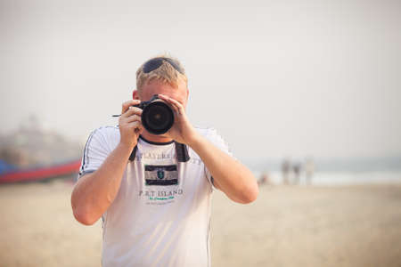 Young man in white getting some photographs with beach backgroundの写真素材