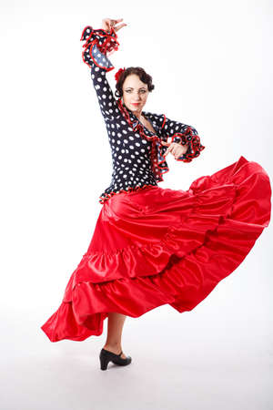 young beautiful brunette female spanish flamenco dancer in black shirt and red flamenco skirt dancing with her arms in studio on gray backgroundの写真素材