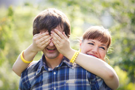 young beautiful brunette girl in blue dress play with her handsome man in blue shirt in green gardenの写真素材
