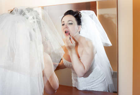beautiful brunette bride in wedding dress look at the mirrorの写真素材