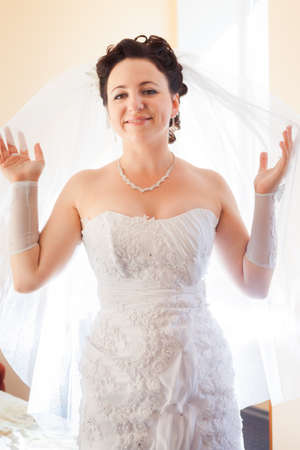 beautiful brunette bride in wedding dress and white vail look at the cameraの写真素材