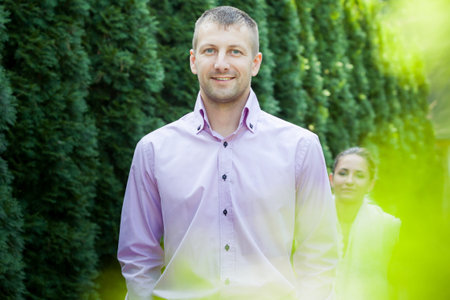 handsome man in pink shirt look at the camera with green trees on background