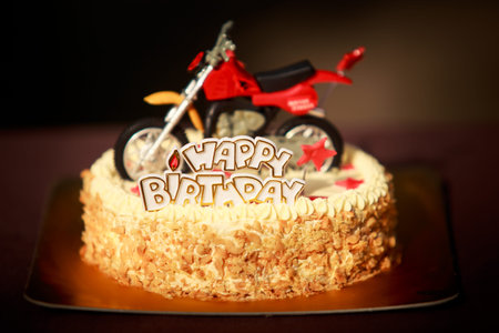 Birthday cake with nuts and vanilla cream decorated with motorcycle figure, red stars and words...