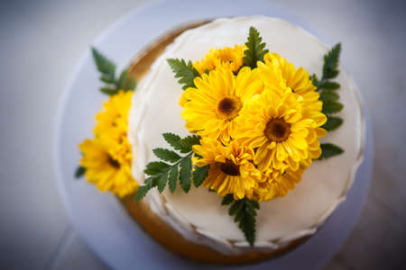 white creamy delicious cake decorated with yellow flowers and green leafsの写真素材