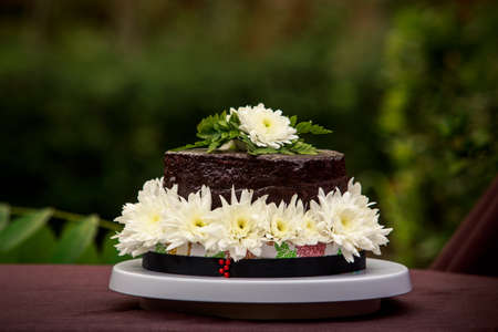 chocolate delicious cake decorated with white flowers and green leafsの写真素材