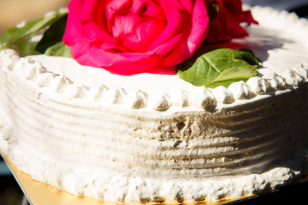 closeup beautiful white creamy delicious cake decorated with three red roses on the top