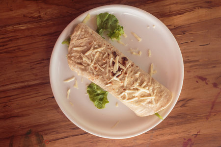 pita bread with cheese and green parsley on white plate stand on wooden table