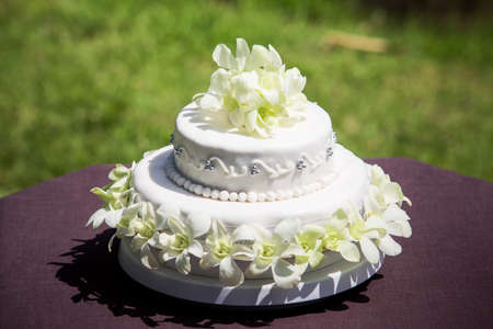 general view of large white wedding cake with white orchids and pearlsの写真素材