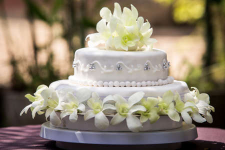 view of large white wedding cake with white orchids and pearlsの写真素材