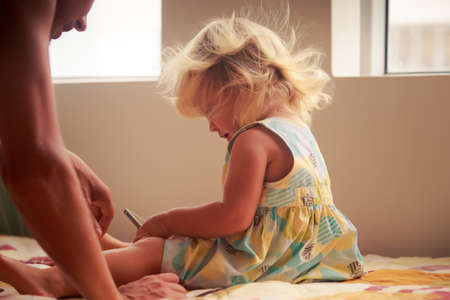 blonde two years old girl plays with smartphone and her fatherの写真素材