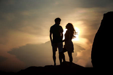 silhouette of kissing guy and girl against sun at dawnの写真素材