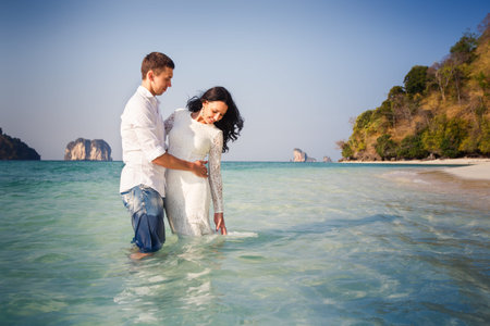 bride and groom hug half in transparent water against cliffsの写真素材